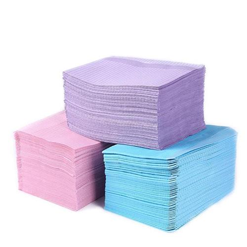 Three stacks of dental bibs in different colors