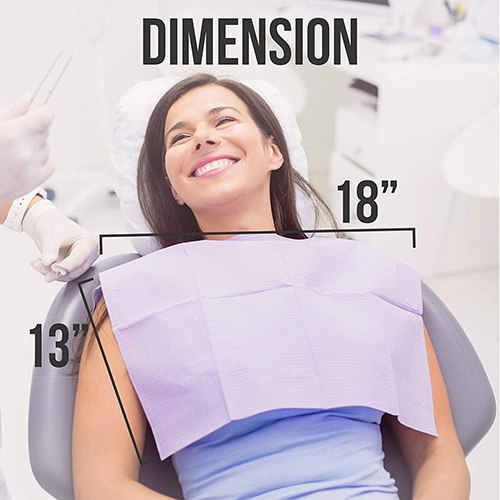 A smiling patient sitting in a dental chair with a dental bib